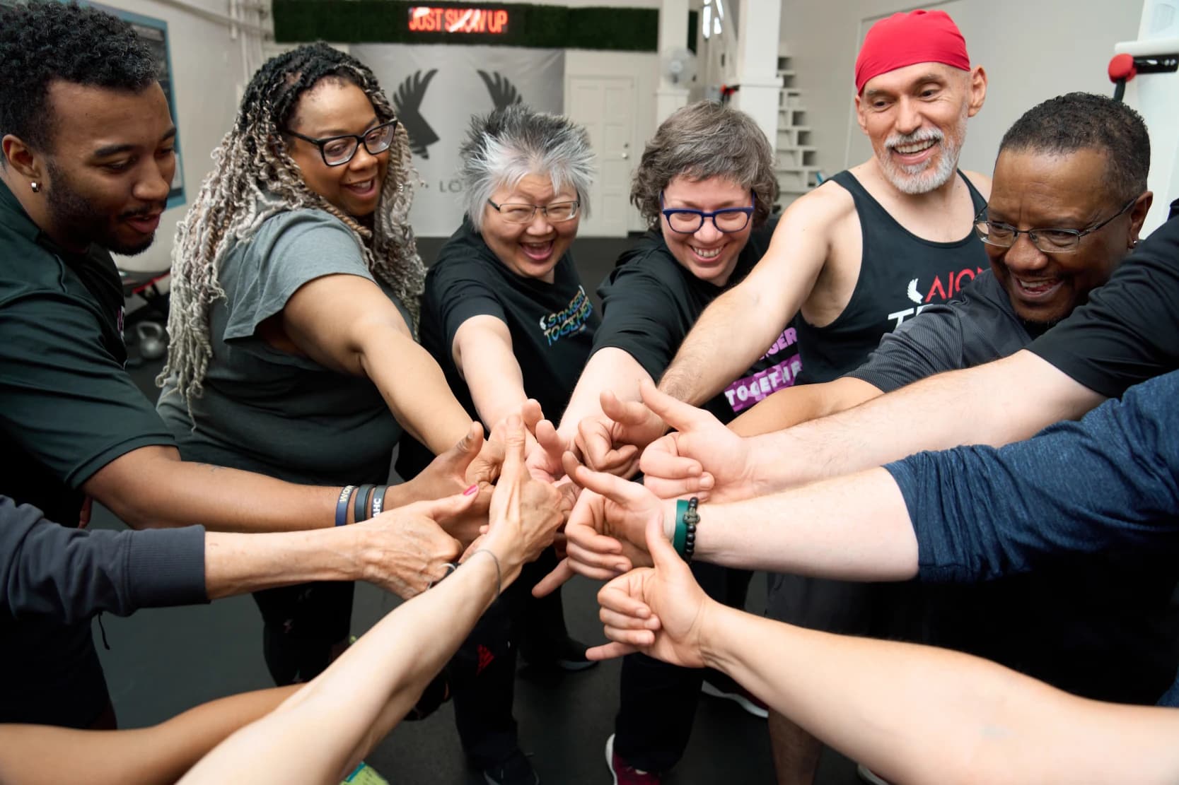 Members and coaches stack their hands together in a circle at the end of a session.
